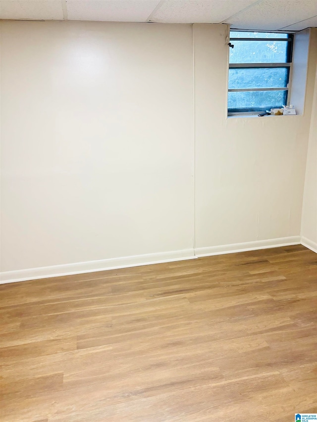 spare room with a paneled ceiling and light wood-type flooring