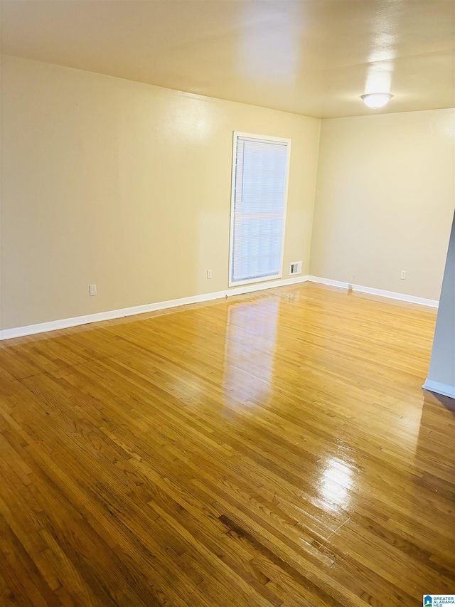 unfurnished room with light wood-type flooring, visible vents, and baseboards