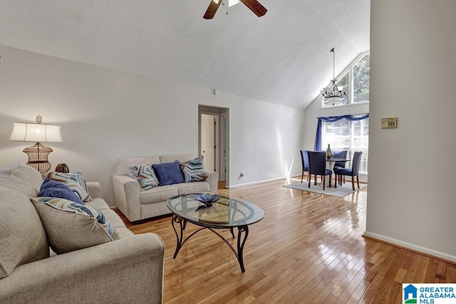 living room featuring ceiling fan, lofted ceiling, a textured ceiling, and light wood-type flooring