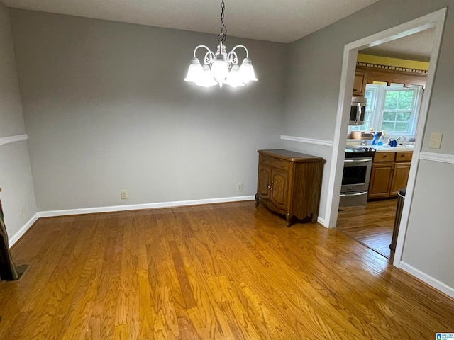 unfurnished dining area with a chandelier and wood-type flooring