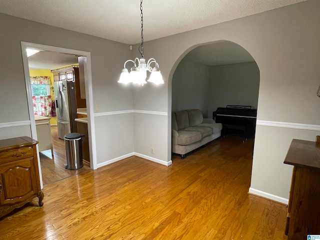 dining area with a textured ceiling, an inviting chandelier, and hardwood / wood-style floors