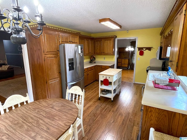 kitchen featuring a textured ceiling, stainless steel fridge, an inviting chandelier, and hardwood / wood-style flooring