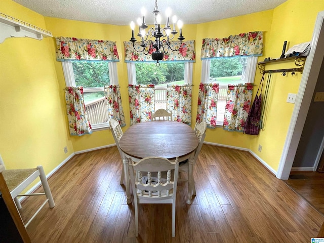 dining space with hardwood / wood-style flooring, a textured ceiling, and a chandelier