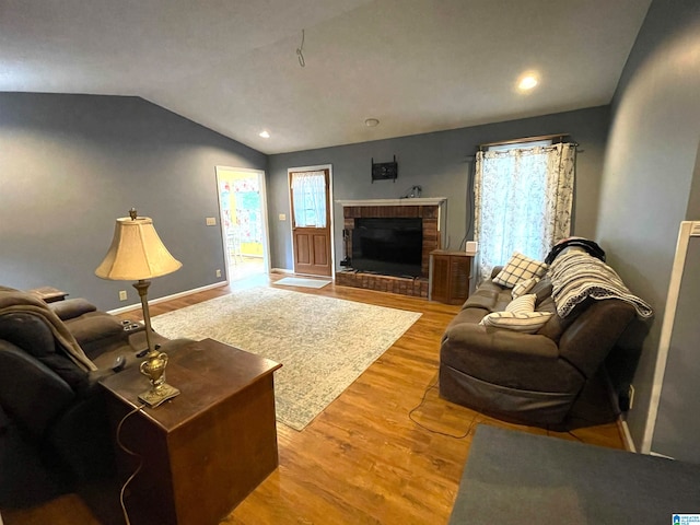 living room with a fireplace, light hardwood / wood-style floors, and vaulted ceiling