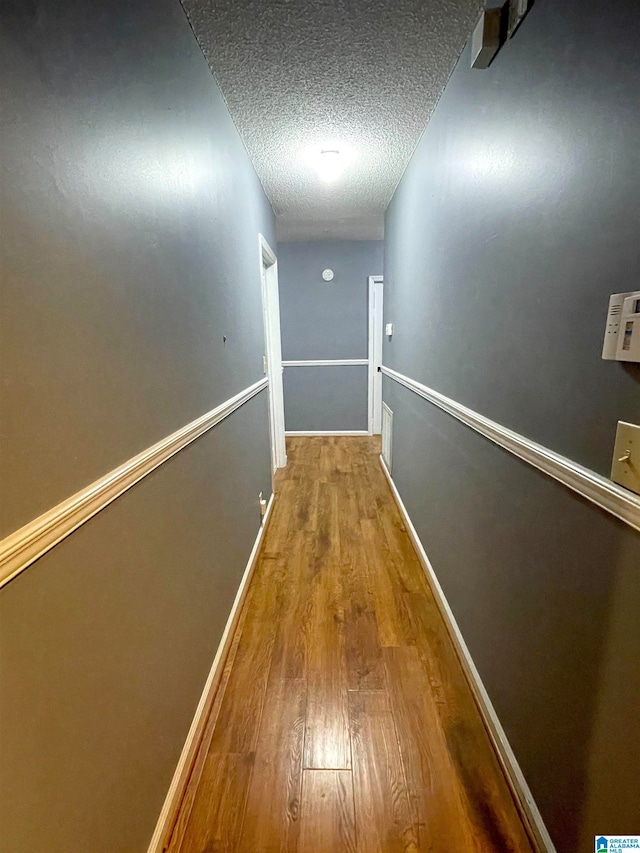 hall with hardwood / wood-style flooring and a textured ceiling