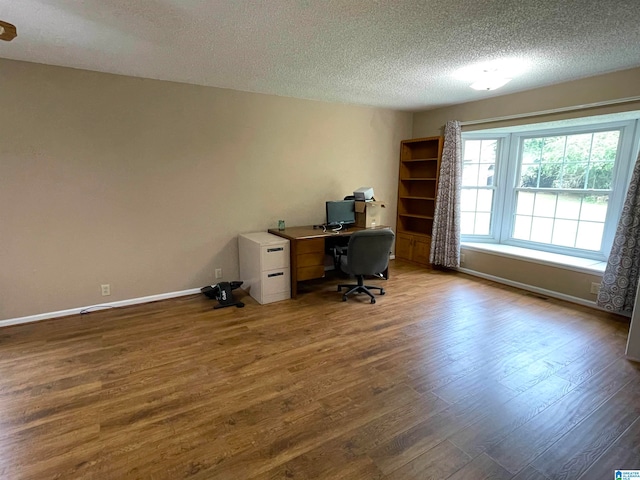 unfurnished office with a textured ceiling and hardwood / wood-style floors