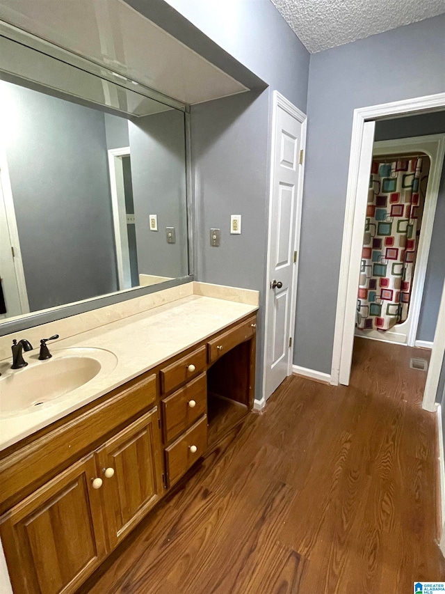 bathroom with a textured ceiling, vanity, and hardwood / wood-style floors