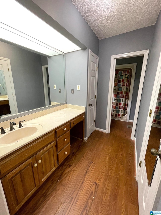 bathroom with a textured ceiling, vanity, and wood-type flooring