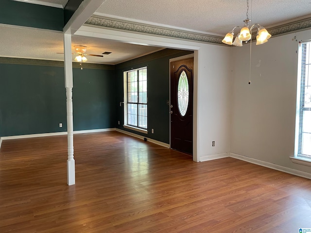 entrance foyer with plenty of natural light, crown molding, ceiling fan with notable chandelier, and wood-type flooring