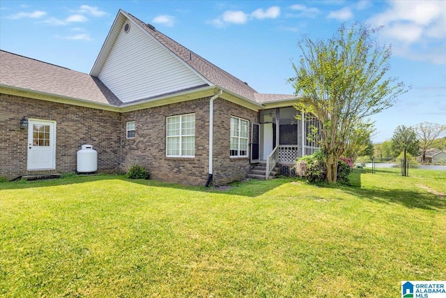 view of side of home with a sunroom and a lawn