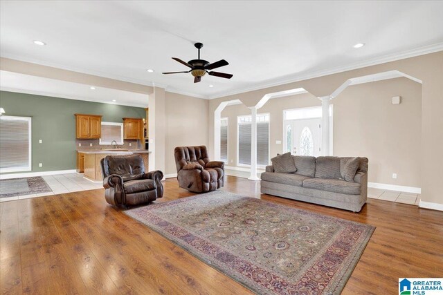 living room with ceiling fan, sink, crown molding, and light hardwood / wood-style flooring