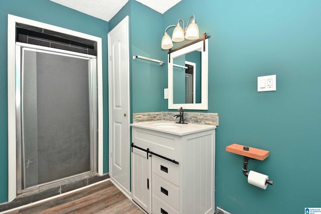 bathroom with a textured ceiling, a shower with door, hardwood / wood-style flooring, and vanity