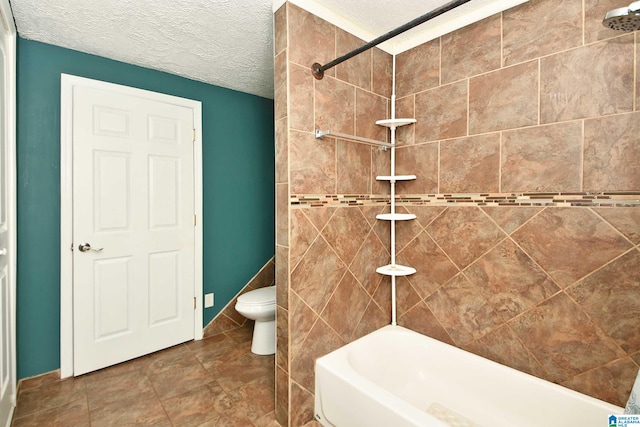 bathroom with tiled shower / bath, toilet, a textured ceiling, and tile patterned floors