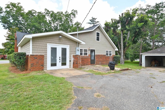 view of front of property featuring a front lawn, an outdoor structure, french doors, and a garage