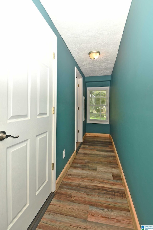 corridor featuring a textured ceiling and dark hardwood / wood-style flooring