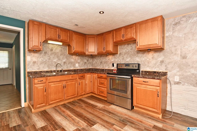 kitchen with hardwood / wood-style flooring, sink, a textured ceiling, and electric stove