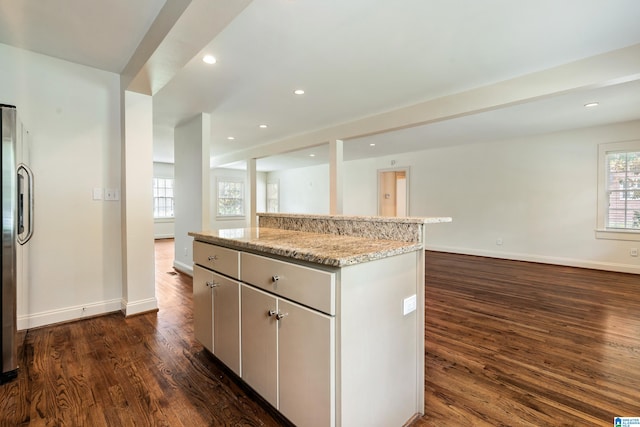 kitchen with light stone countertops, dark hardwood / wood-style flooring, and a kitchen island