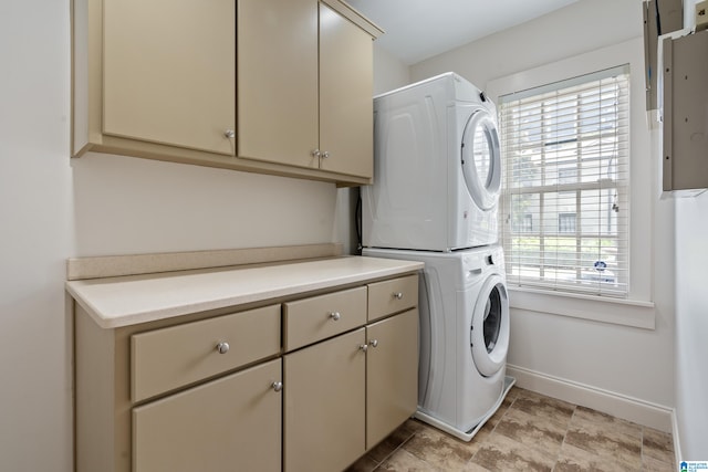 washroom with light tile patterned floors, stacked washer / drying machine, and cabinets