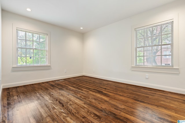 empty room with plenty of natural light and dark hardwood / wood-style flooring