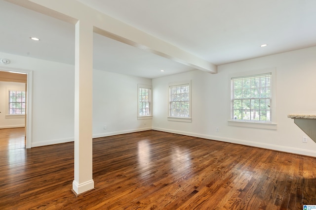 unfurnished living room featuring beam ceiling and dark hardwood / wood-style floors