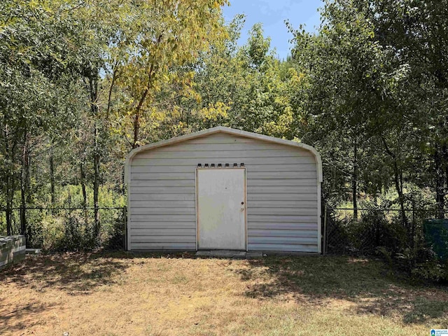 view of shed featuring fence and a view of trees