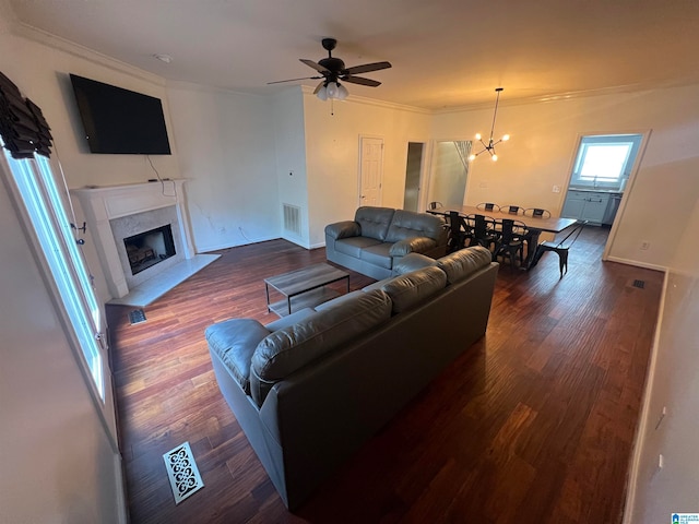 living room with ceiling fan with notable chandelier, ornamental molding, a high end fireplace, and dark hardwood / wood-style flooring