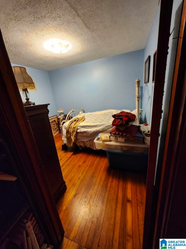 bedroom with hardwood / wood-style floors and a textured ceiling