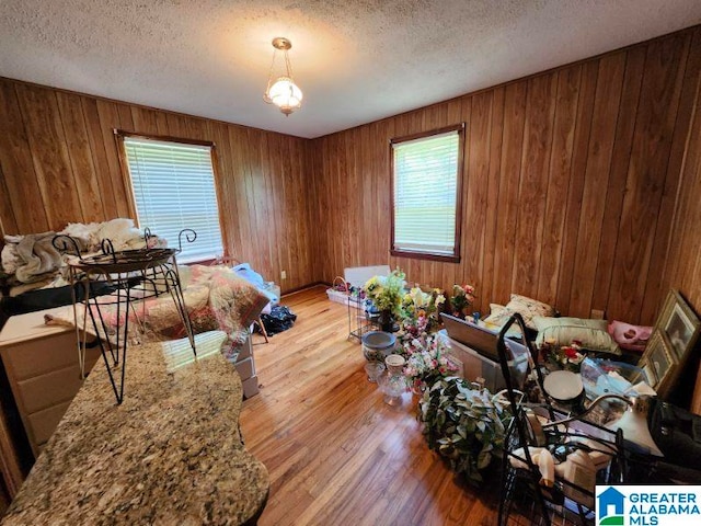 miscellaneous room with a textured ceiling, light hardwood / wood-style flooring, and wood walls