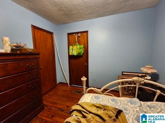 bedroom with a textured ceiling and dark hardwood / wood-style flooring