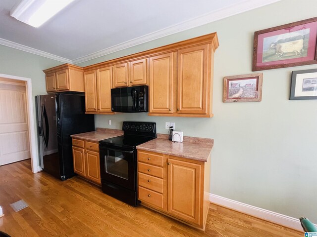 kitchen featuring black dishwasher, sink, light hardwood / wood-style flooring, and ornamental molding