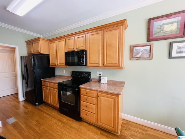 kitchen featuring ornamental molding, light countertops, light wood-style flooring, and black appliances