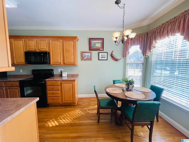 kitchen with crown molding, black appliances, light hardwood / wood-style floors, and a chandelier