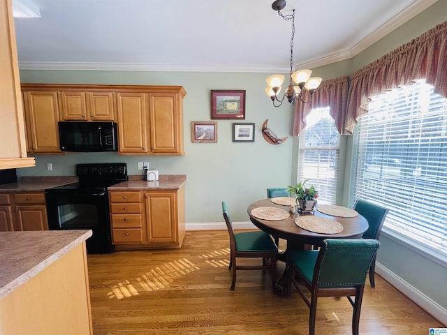 kitchen featuring a notable chandelier, light wood-style floors, hanging light fixtures, ornamental molding, and black appliances