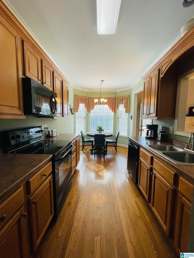 kitchen featuring a notable chandelier, ornamental molding, black appliances, and wood-type flooring