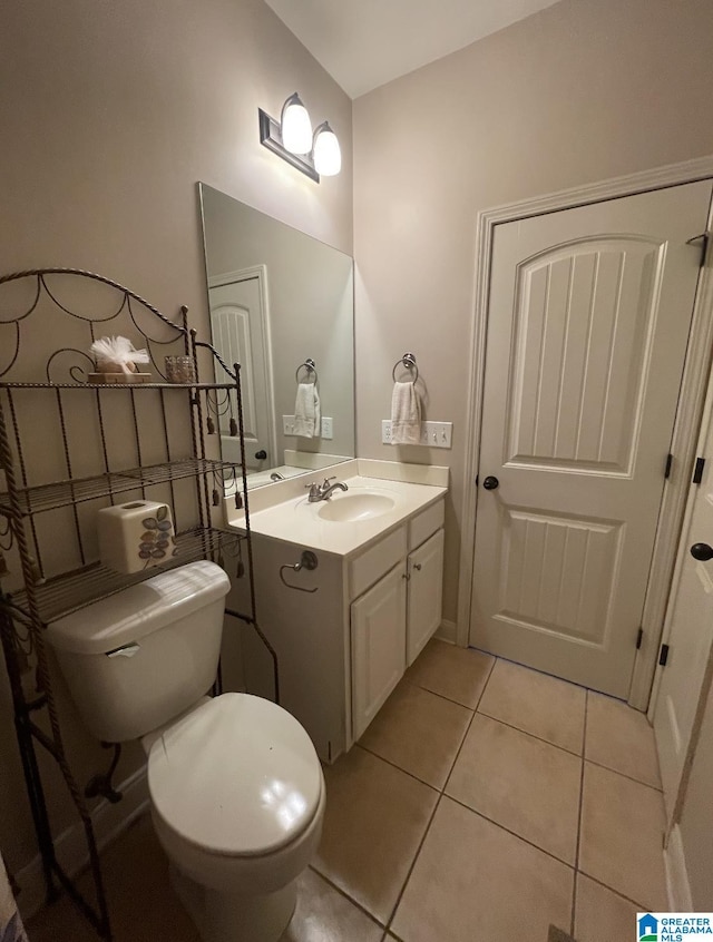 bathroom with toilet, vanity, and tile patterned floors