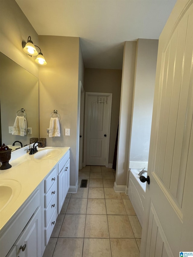 bathroom featuring double vanity, tile patterned flooring, a sink, and baseboards