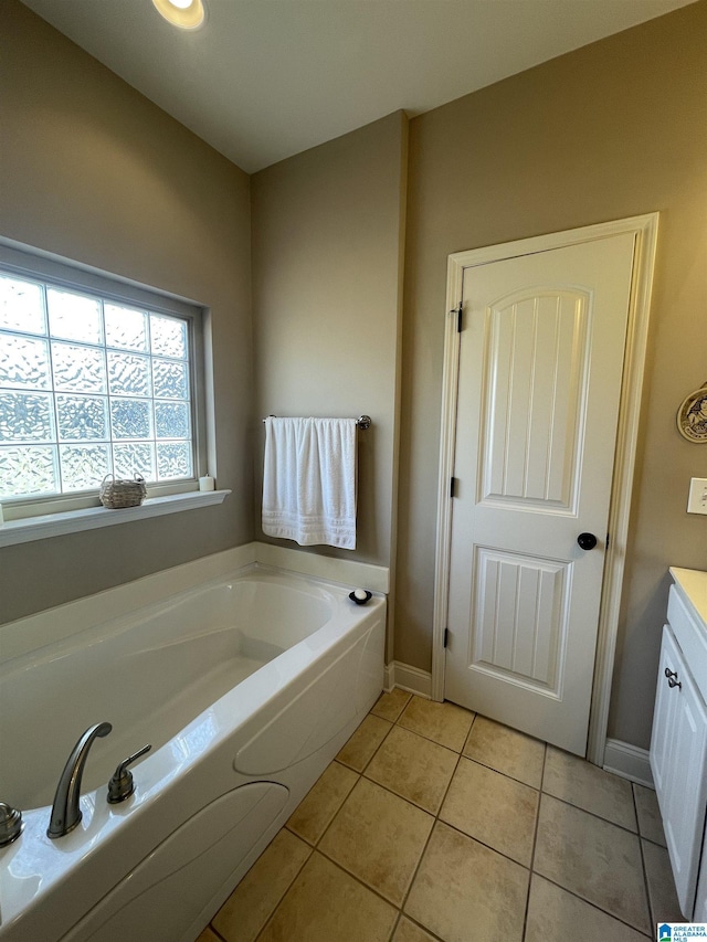 full bathroom with a garden tub, vanity, baseboards, and tile patterned floors