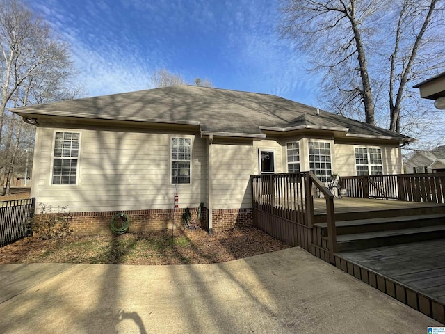 back of house with a shingled roof and a wooden deck