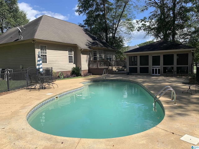 view of swimming pool featuring a fenced in pool, a sunroom, fence, a deck, and a patio area