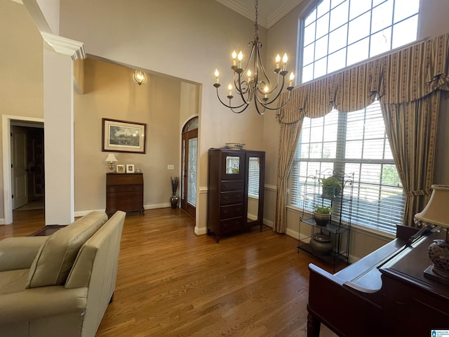 interior space featuring ornamental molding, arched walkways, a high ceiling, and wood finished floors