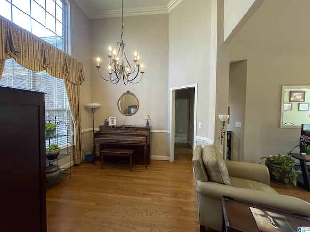 interior space featuring ornamental molding, a high ceiling, an inviting chandelier, and wood finished floors