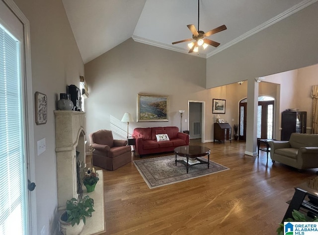 living room with arched walkways, ceiling fan, ornamental molding, wood finished floors, and high vaulted ceiling