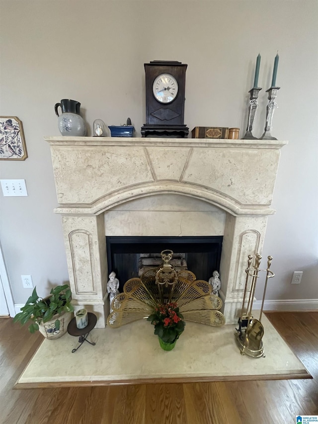 interior details featuring a fireplace, wood finished floors, and baseboards