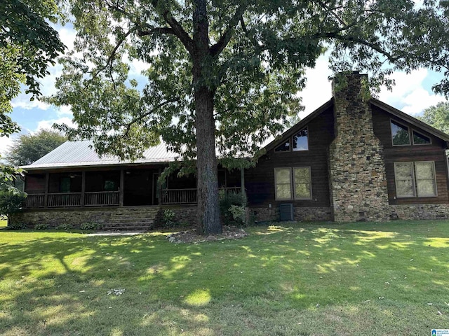 view of front of property with a front lawn, a porch, metal roof, and a chimney