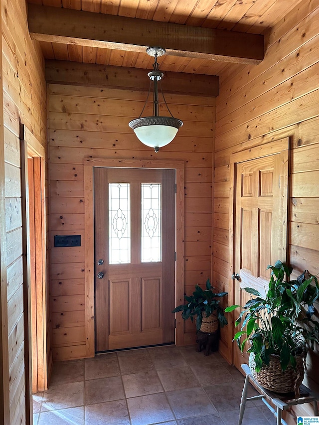 tiled entrance foyer with beam ceiling, wood walls, and wood ceiling