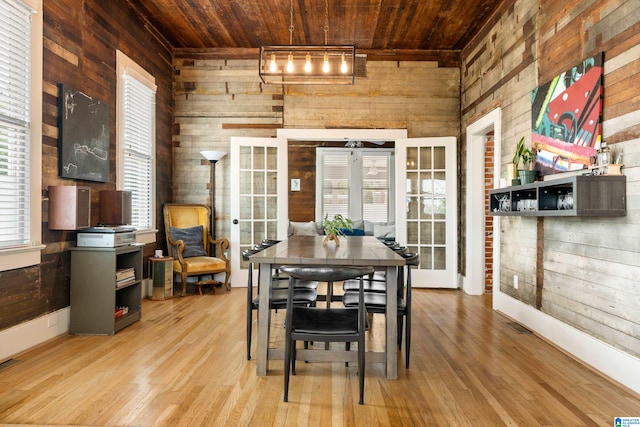 dining space featuring french doors, wood walls, light hardwood / wood-style floors, and wooden ceiling