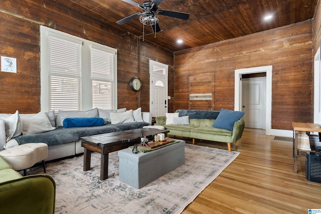 living room featuring light hardwood / wood-style flooring, ceiling fan, wood walls, and wooden ceiling