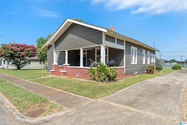 view of side of home featuring a yard and covered porch