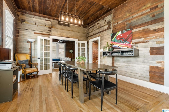 dining area with wood ceiling, french doors, wooden walls, and light hardwood / wood-style floors