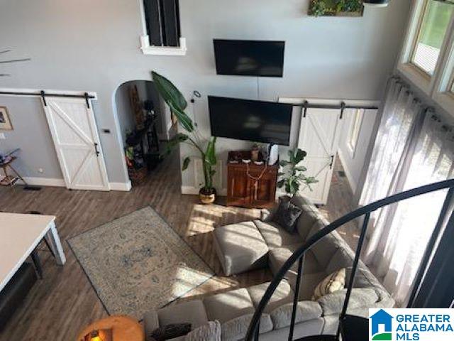 living room with a barn door and wood-type flooring